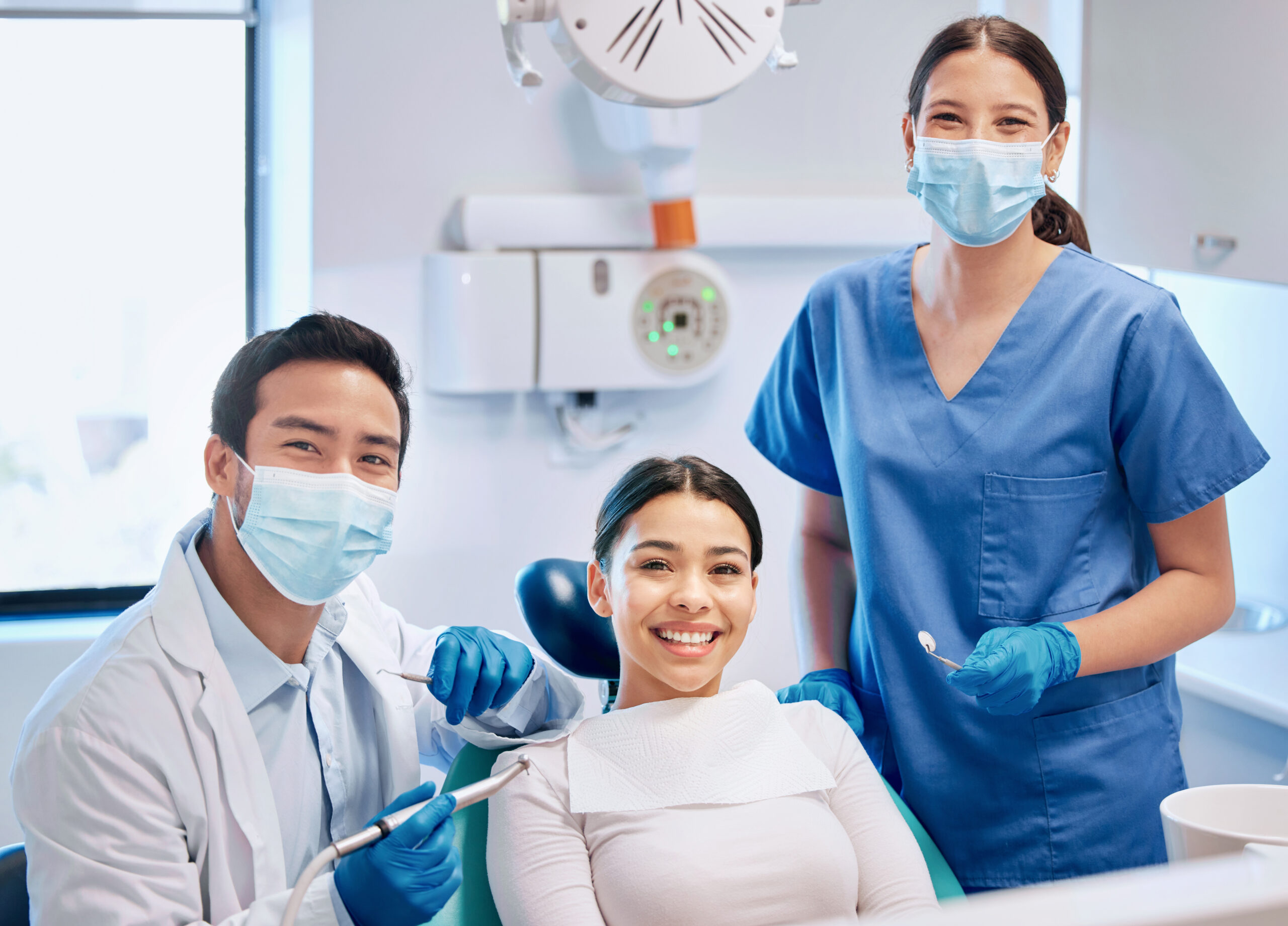 Dentist and dental assistant with a smiling patient in a clinic, showcasing professional oral care expertise.