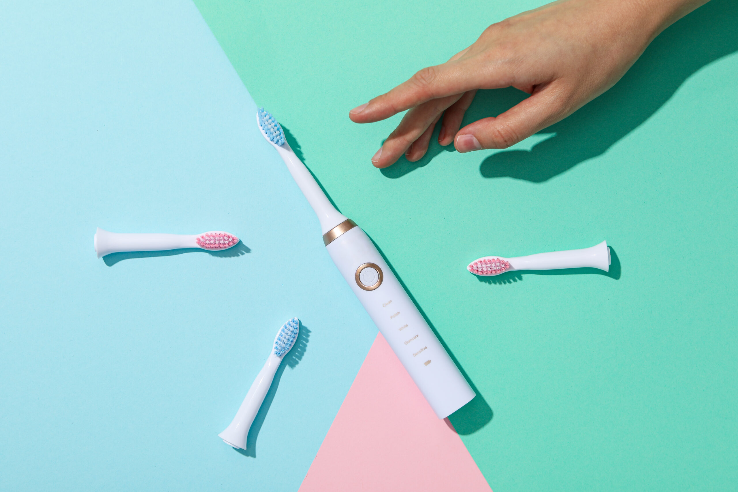 Electric toothbrush with replaceable brush heads on colorful background