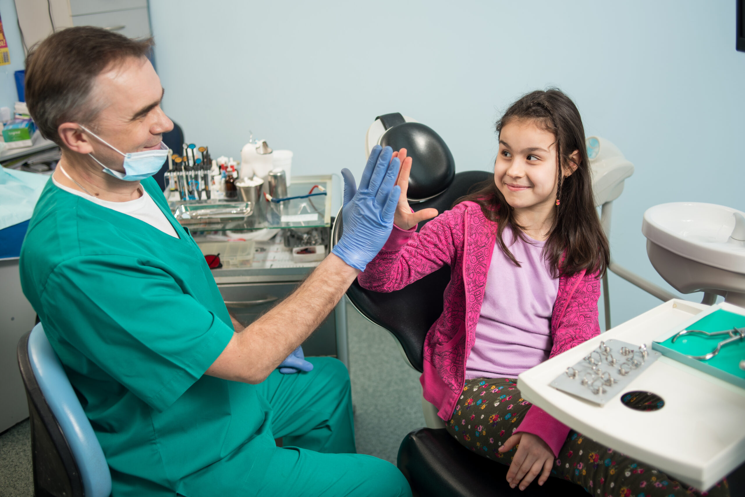Dentist teaching a child proper brushing techniques with a model during a pediatric dentistry appointment.