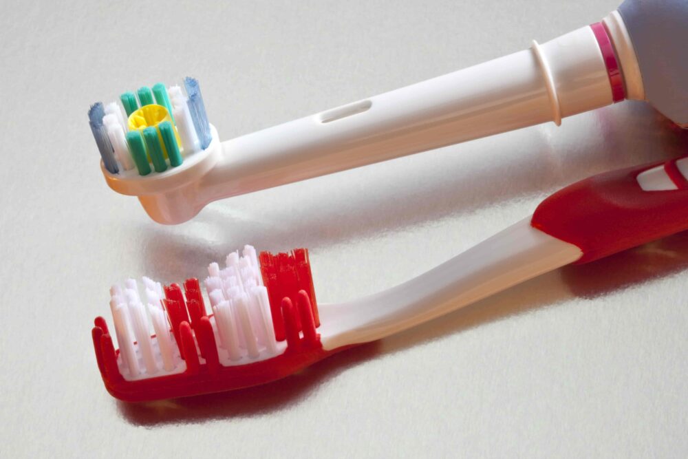Comparison of an electric toothbrush head and a manual toothbrush on a white background