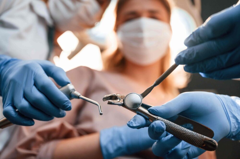 Dentists preparing for a wisdom tooth removal procedure with dental tools and a patient in the background