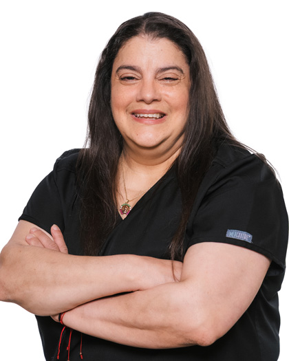 Jeannette Smith, Business Associate at Pecan Tree Family Dentistry, smiling with her arms crossed while wearing black scrubs against a white background.