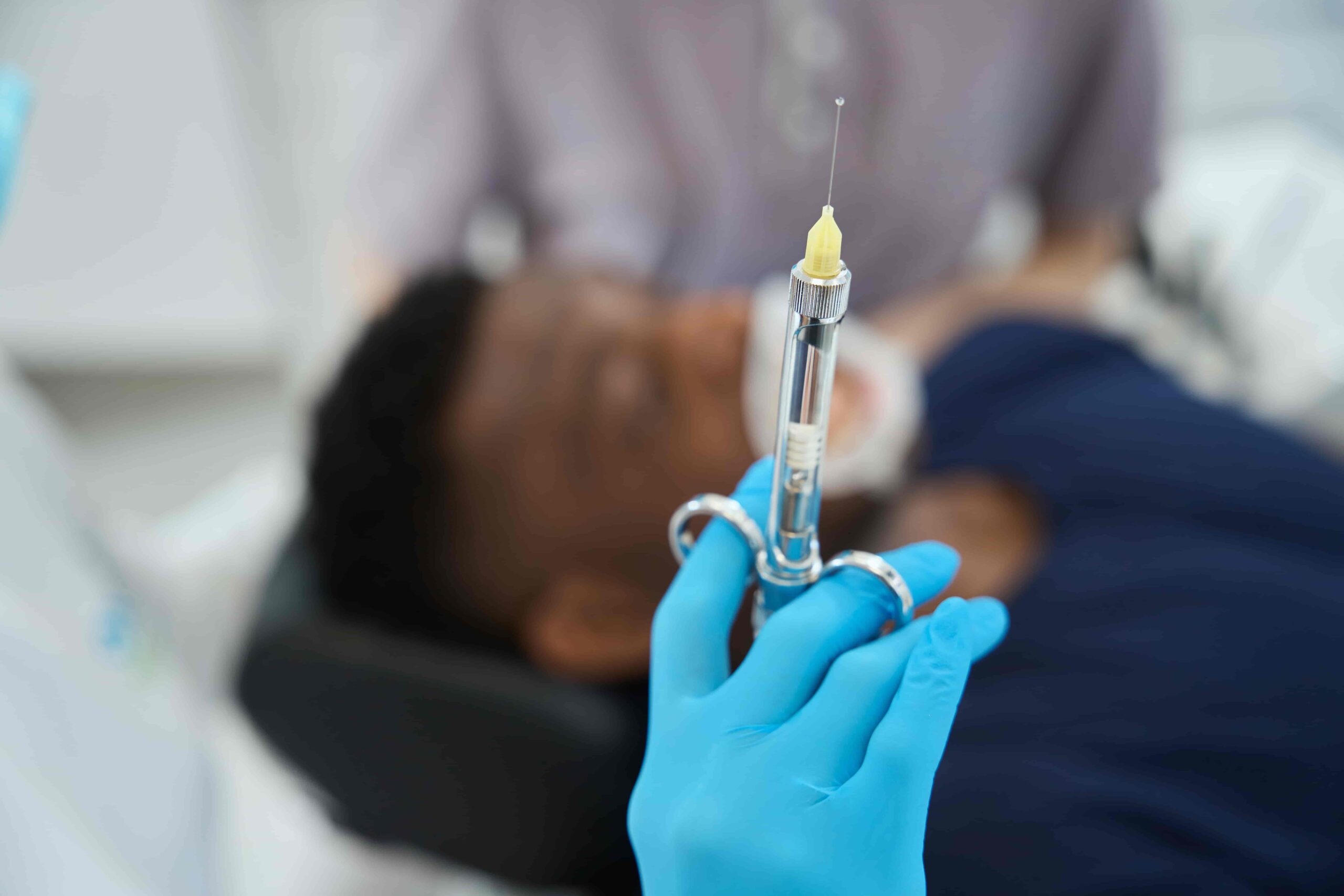 Dentist holding a syringe filled with local anesthetic before administering an injection to a patient