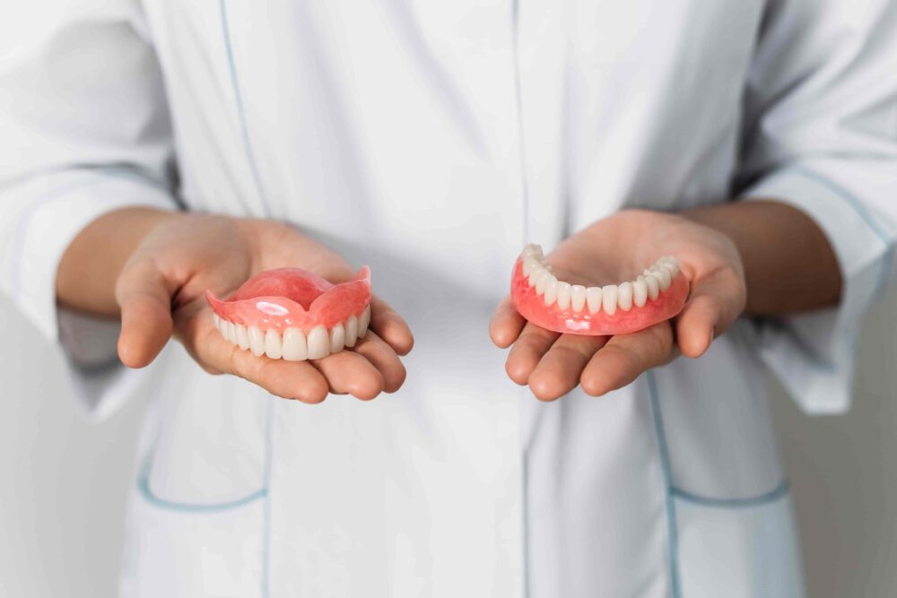 Dentist holding a pair of upper and lower dentures in both hands for patient education