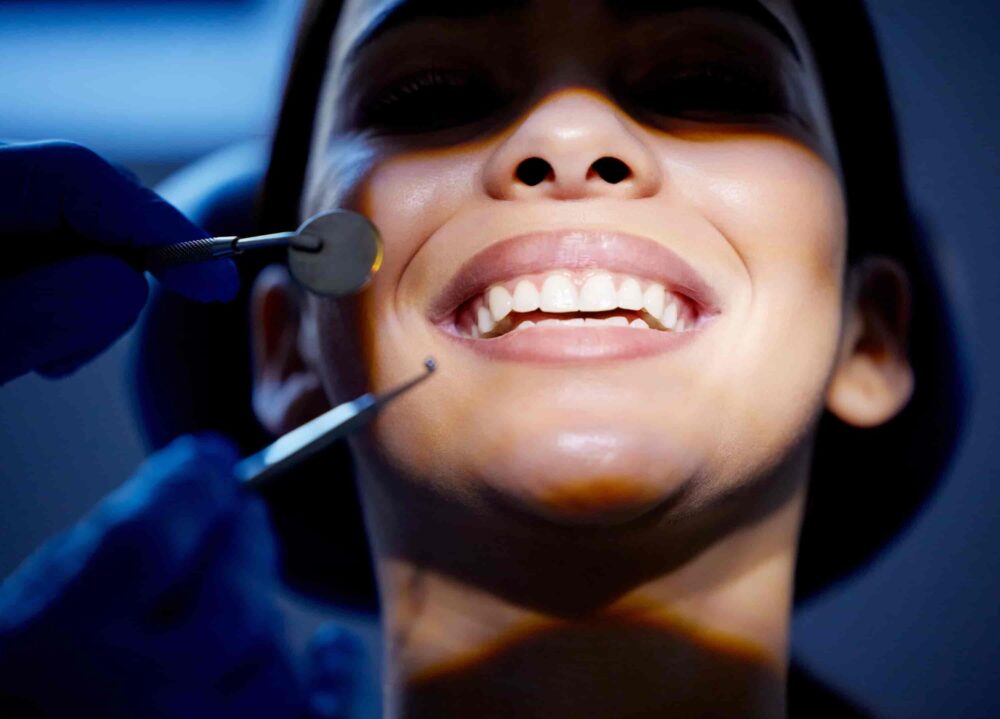 Woman smiling confidently in a dental chair during a teeth whitening treatment