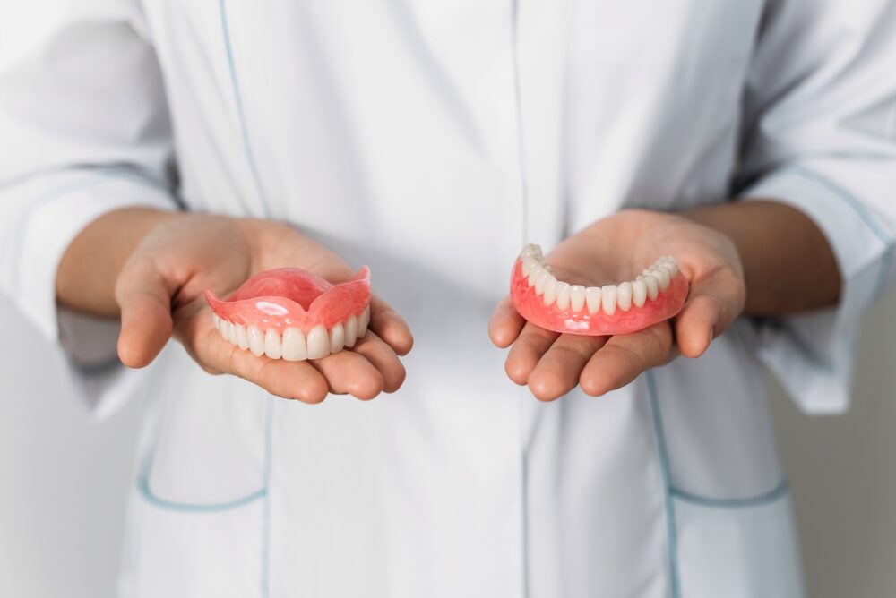 Dentist holding upper and lower complete dentures at Pecan Tree Family Dentistry in McKinney, TX