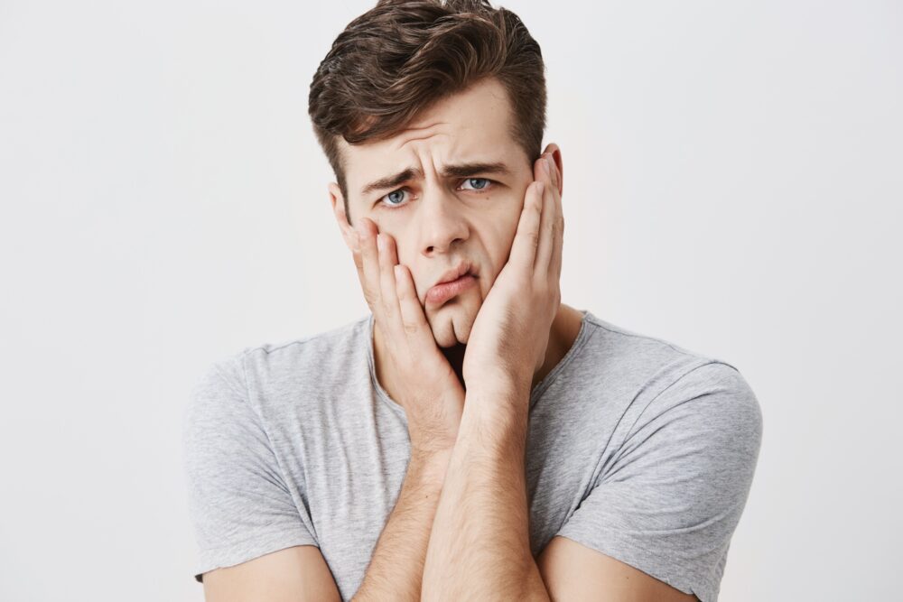 Man looking stressed while holding his jaw due to dental discomfort